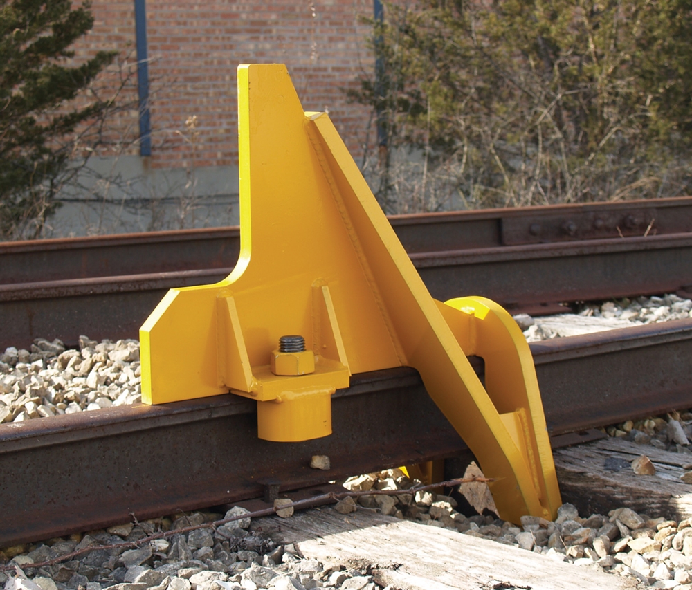 Uses the cushioning capacity of the tie and a wheel-bump feature to lift the wheel slightly off the rail to absorb momentum of moving car. Recommended for industrial spur tracks which do not require a bumping post but which need more protection.